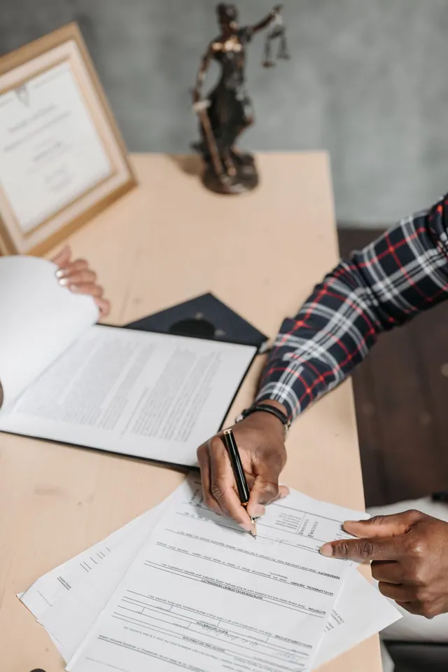 Main signant un document sur un bureau, illustration des relations de travail